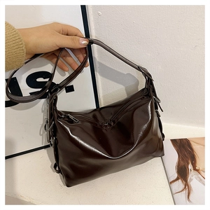 Detail of dark brown patent leather tote with glossy finish and silver metal rings