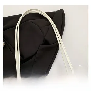 Detail of light blue canvas bag featuring white leather handles and a delicate lace bow