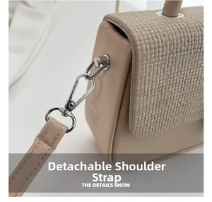 Detail showing the detachable shoulder strap with silver metal hooks and woven texture