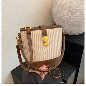 Close-up of contrast stitching bucket bag with woven texture and gold metal twist lock