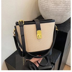 Close-up of straw patchwork bucket bag with black leather trim and gold metal hardware