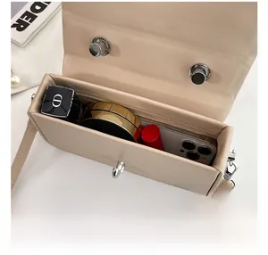 Internal capacity of beige small square bag showing lipstick, phone, and powder storage