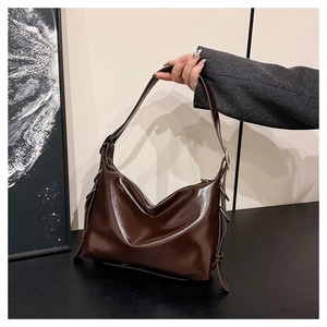 Close-up of glossy dark brown PU leather hobo bag with adjustable metal buckle detail