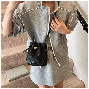 Close-up of black snake texture bucket bag with golden metal twist lock and slim strap