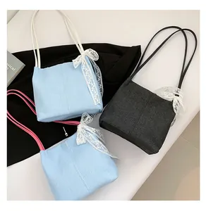 Three denim tote bags in light blue and grey featuring delicate white lace bow details