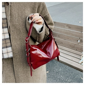 Detail of red glossy leather tote bag with metal buckle and adjustable shoulder strap