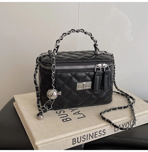 Detail of black quilted leather handbag with silver chain handle and metal ball adjuster