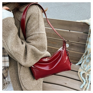 Detail of a burgundy patent leather tote bag on a wool coat during outdoor photoshoot