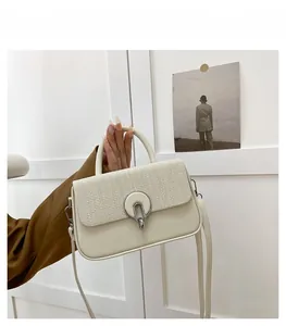 Detail of minimalist cream leather handbag with tweed flap and silver clasp held by model