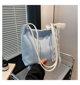 Detail of light blue denim tote with white leather straps and elegant lace bow accent