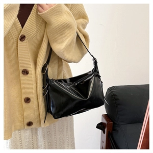 Close-up of black glossy tote bag with pleated texture and silver hardware detail