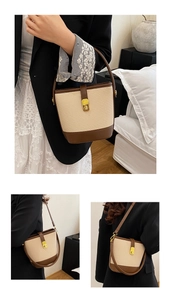 Detail of woven bucket bag with brown leather trim and golden buckle closure