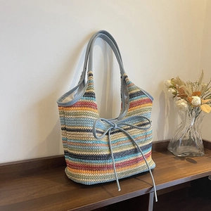 Colorful striped woven straw tote bag with leather handles and decorative bow detail