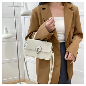 Detail of cream leather crossbody bag with woven texture flap and silver buckle detail