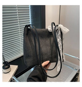Detail of black canvas tote bag with elegant white floral lace bow on the side