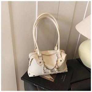 Nahaufnahme der cremefarbenen Handtasche mit Perlenkette und silbernen Nieten-Details