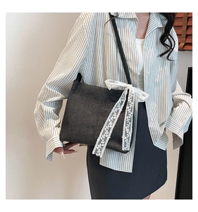Detail of dark denim tote bag with white lace bow and blue striped shirt styling