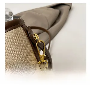 Detail of high-quality gold metal hook on straw and brown leather bucket bag