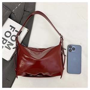 Detail of burgundy glossy tote bag with silver side buckle and wide shoulder strap