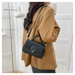 On-model view of black crossbody bag featuring woven texture and silver ring buckle