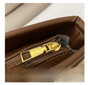 Detailed macro of smooth gold metal zipper and premium brown leather trim on bag