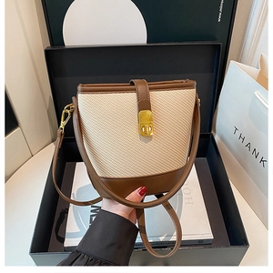Detail of a straw patchwork bucket bag with leather trim and golden metal lock