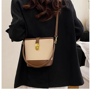 Detail of woven bucket bag with brown leather trim and gold lock shown on model