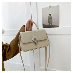 Detailed view of beige crossbody bag featuring textured weave and large silver metal lock