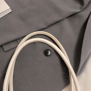 Detail showing the sturdy dual-handle design and precise stitching on the white handbag