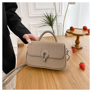 Detail of minimalist beige crossbody bag featuring houndstooth texture and silver ring lock