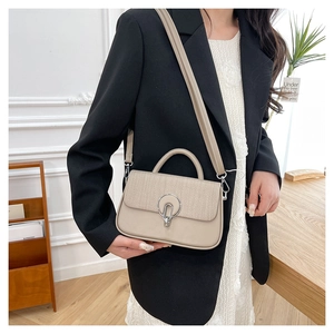 Detail of light beige crossbody bag featuring woven texture and silver ring metal clasp