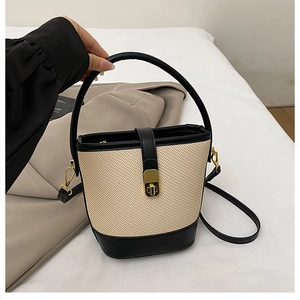 Detail of minimalist contrast-color bucket bag with gold hardware and leather trim