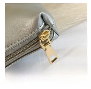 Detailed close-up of smooth gold metal zipper on silver leather evening bag texture