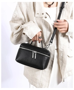 Model wearing a black pebble leather crossbody bag with silver zippers and top handle
