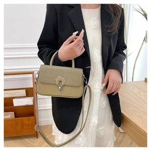 Close-up of olive green crossbody bag with woven flap detail and silver metal buckle