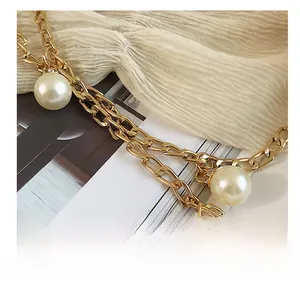 Detail shot of large faux pearl pendants on a gold chain necklace with sparkling rhinestones