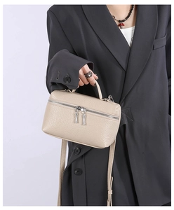 Close-up of beige lychee-textured crossbody bag on a model wearing a grey blazer