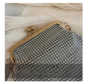 Detail of silver rhinestone evening clutch with gold spherical clasp and metal chain