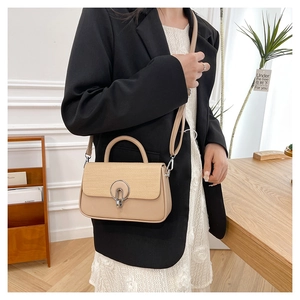 Detail view of khaki square bag featuring woven flap and silver round ring metal buckle