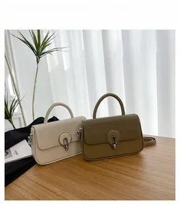 Detail of minimalist cream and khaki handbags with woven texture flap and round metal lock