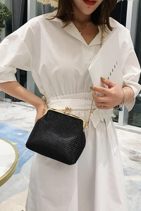 Detail of black rhinestone evening bag with gold shell frame and pearl chain strap