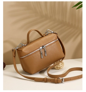 Detailed view of caramel grained leather shoulder bag with dual zippers and silver hardware