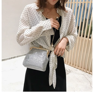 Detail of silver rhinestone evening bag with elegant pearl chain strap on model