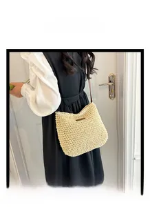 Detailed view of beige woven straw handbag with leather strap and decorative front tag