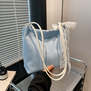 Light blue denim tote bag with white lace bow ribbons on industrial silver cart