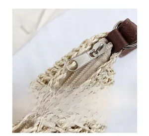 Detail of silver metal zipper and brown leather trim on a woven straw handbag