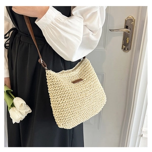 Detail of woven straw shoulder bag with brown leather patch and adjustable metal buckle