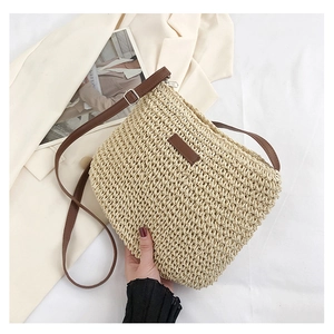 Detail of hand-woven straw crossbody bag with brown leather strap and silver buckle