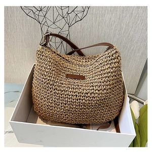 Detail of hand-woven straw shoulder bag with brown leather patch and adjustable strap