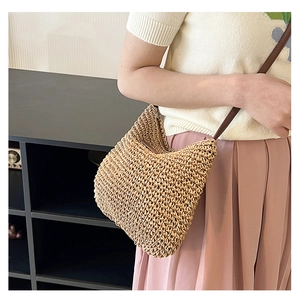 Crossbody straw bag with leather strap and woven texture on a model in casual outfit